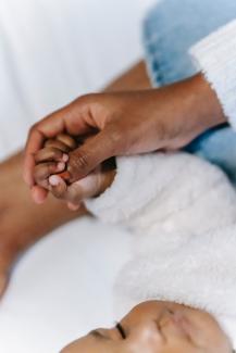 A close up photo of a mother holding hands with her sleeping baby.