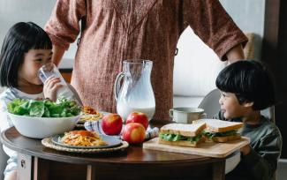 A brother and sister eat a nutritious meal together at a table. 