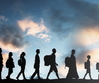 A silhouette picture of people traveling with the sky in the background.  